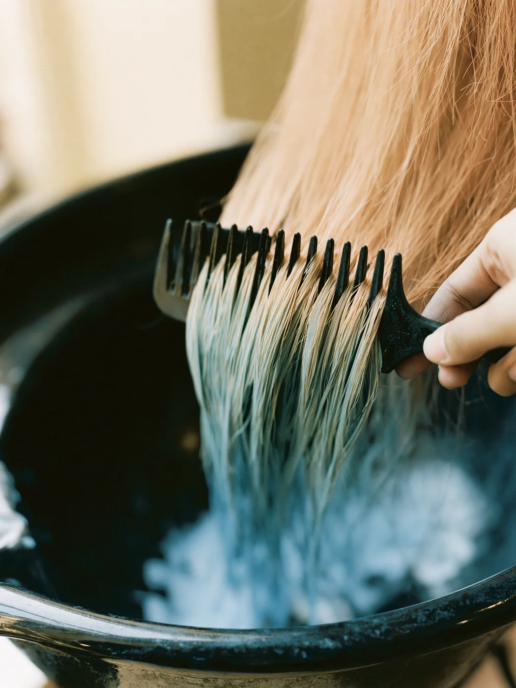 Blauer Toner wird mit der Kammbürste durch kupferblondes Haar gezogen