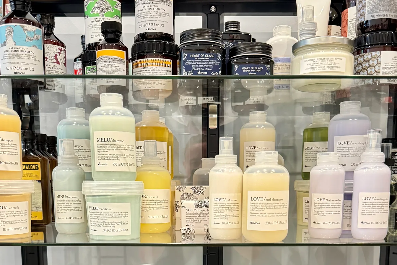 Davines-Pflegeserien im Glasregal des Studios — Shampoos, Masken und Conditioner für trockenes Haar